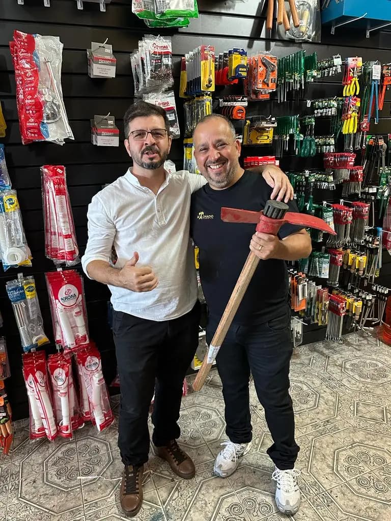 Alexandre Machado na inauguração da loja, diante da parede de ferramentas