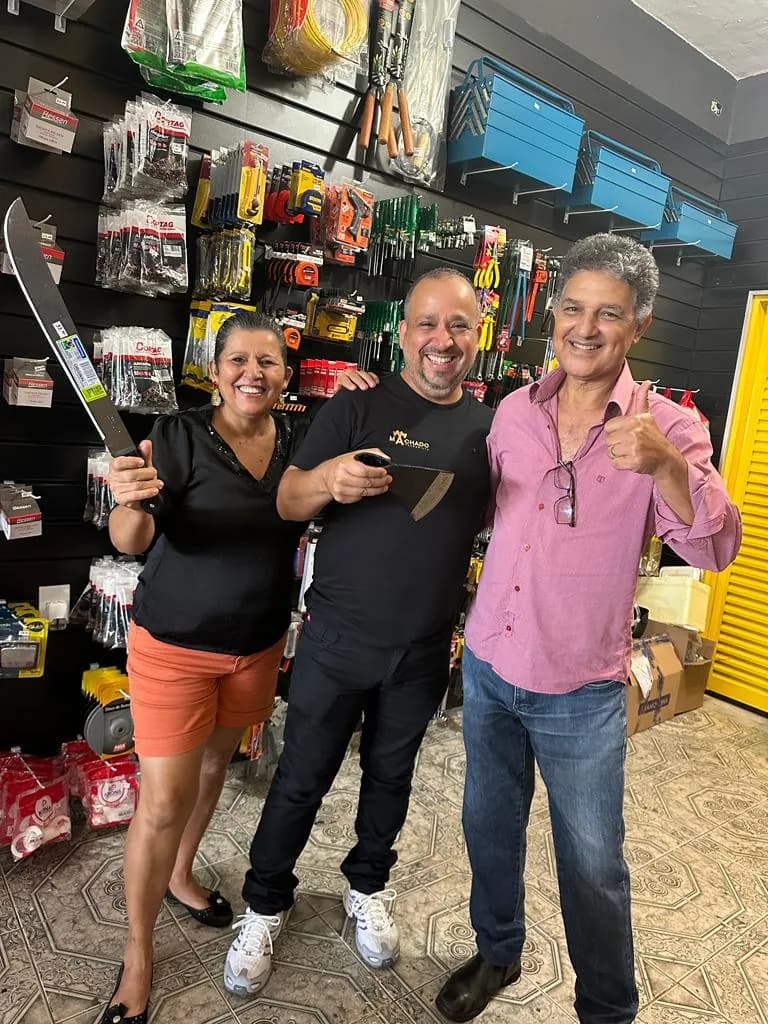 Alexandre Machado com convidados na inauguração da loja, entre facão e ferramentas